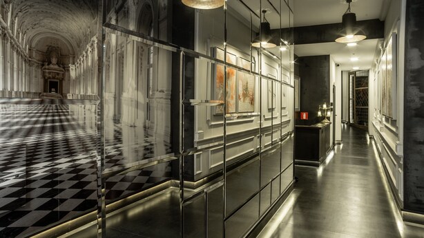 A hallway with a checkered floor, mirrored walls, and modern lighting fixtures. - Libertad 24 (Madrid)