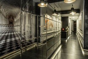 A hallway with a checkered floor, mirrored walls, and modern lighting fixtures. - Libertad 24 (Madrid)