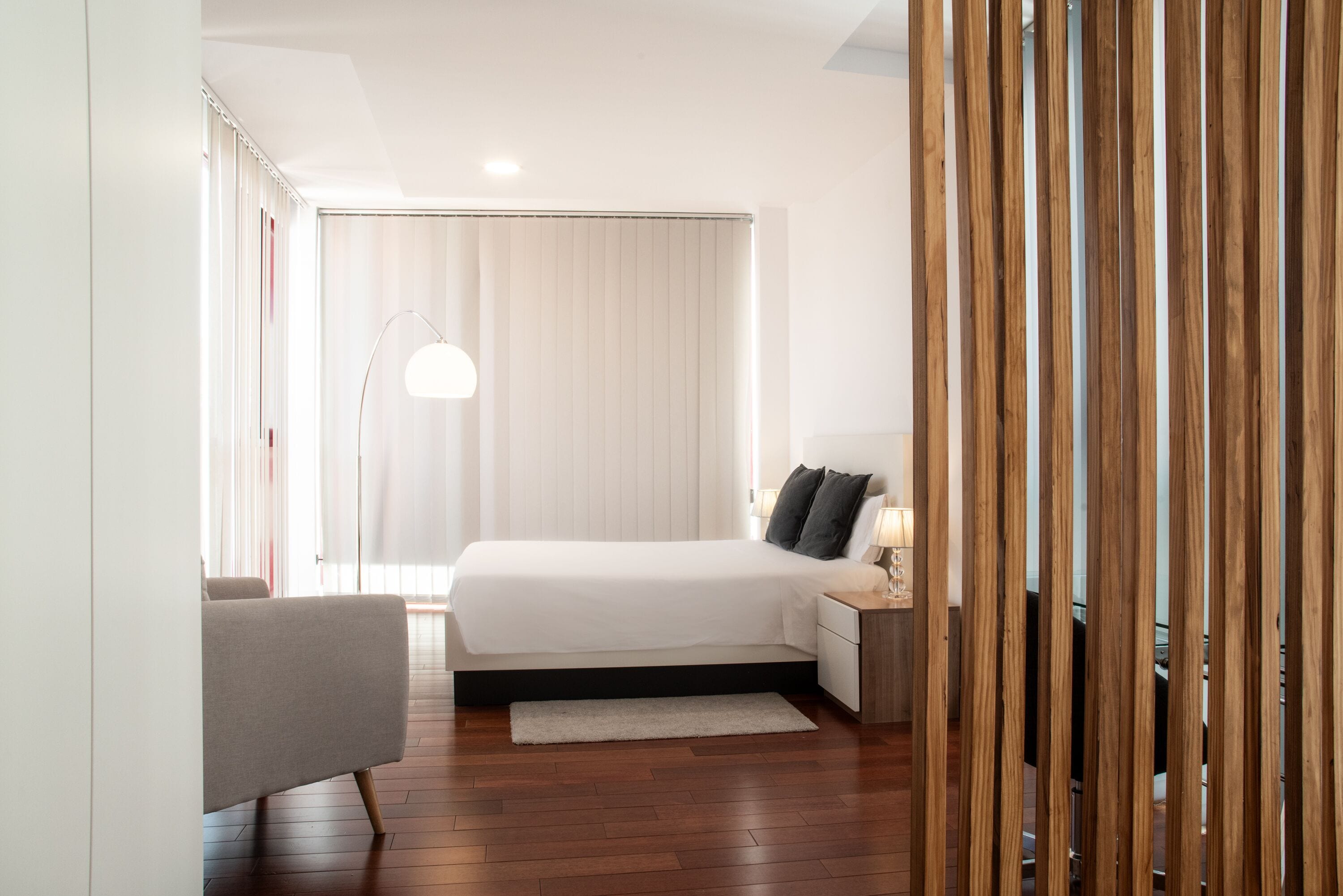 A modern bedroom with a large bed, bedside table, and a lamp.