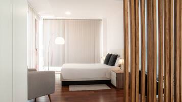 A modern bedroom with a large bed, bedside table, and a lamp.