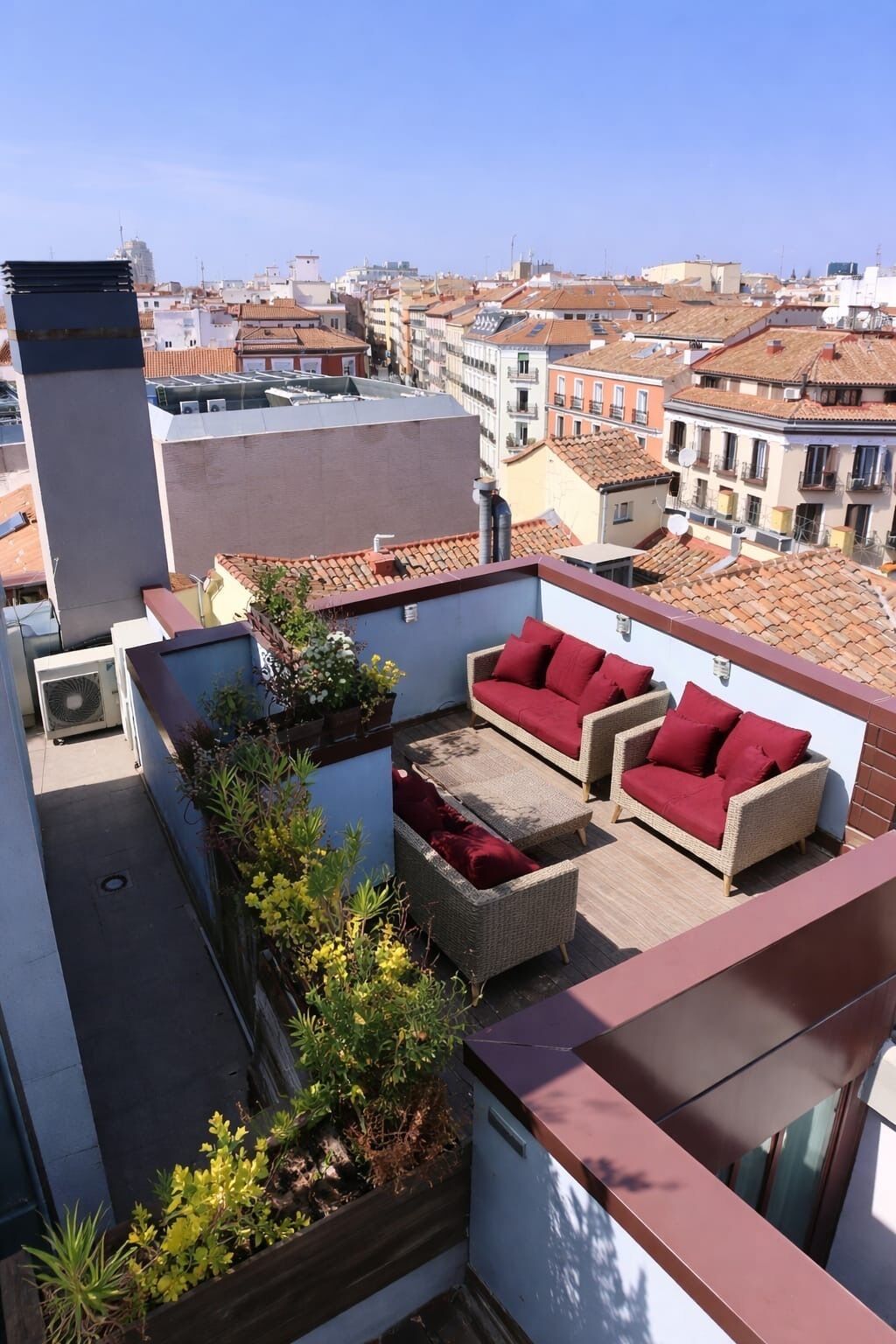 A rooftop terrace with outdoor furniture and plants.