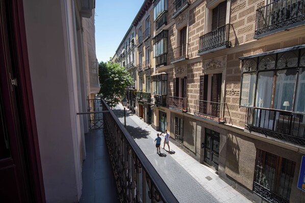 A narrow urban street with multi-story buildings, balconies, and a clear sky. - Libertad 24 (Madrid)