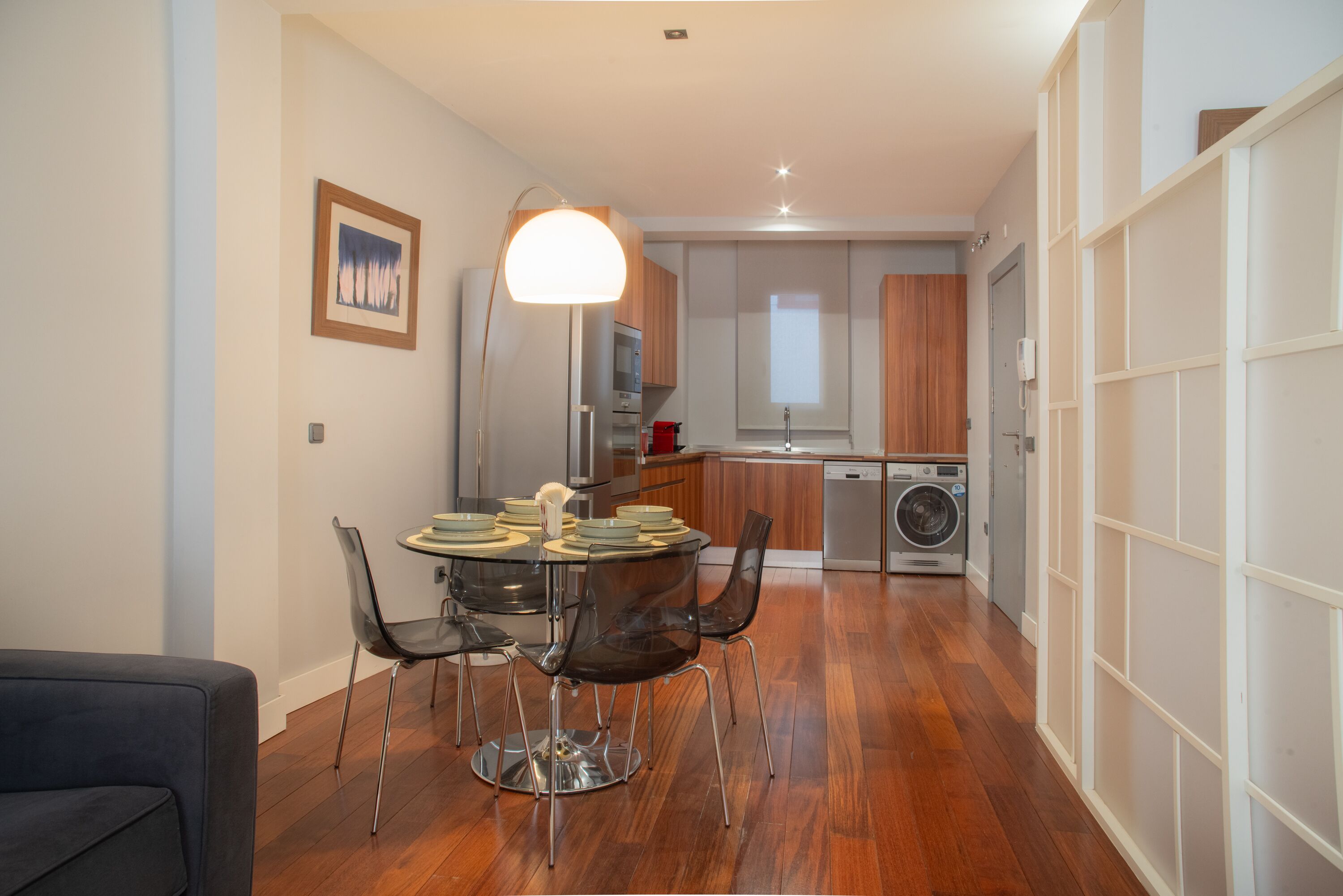 A modern kitchen with wooden cabinets, a built-in oven, and a washing machine.