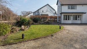 A two-story house with a gravel driveway and a well-maintained lawn. - Robins Perch (Stockport)