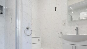 A modern bathroom with a glass shower enclosure, a toilet, and a sink with a mirror above it. - Robins Perch (Stockport)
