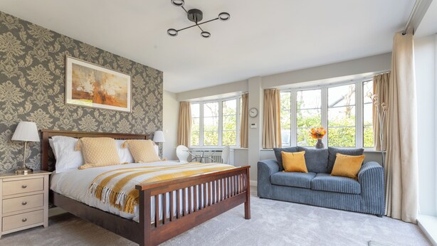 A bedroom with a wooden bed, a sofa, and a desk. - Robins Perch (Stockport)