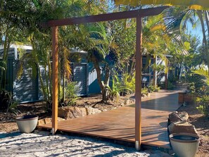 A wooden pergola structure surrounded by tropical plants and a wooden pathway. - Amity Point Waterfornt Cabins - Tamdhu (Amity Point)