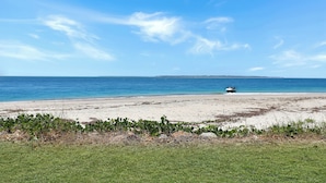 A beach with a boat on the sand, clear sky, and calm sea.