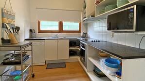 A kitchen with white cabinets, a microwave, a sink, and a window.