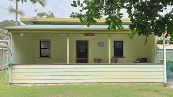 A single-story building with a green facade, a sign reading "SALTYS," and a small porch area.