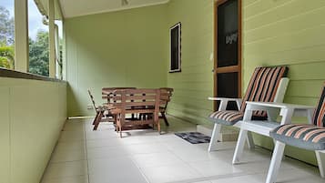 A room with a wooden bench and two striped chairs, a window with a 'Enjoy' sign, and a ceiling fan.