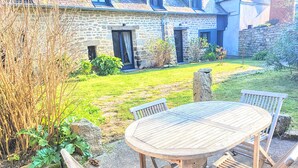 A stone house with a garden, a round wooden table with chairs, and a stone bench. - Charming Breton Penty 40m from the ocean (Penmarc'h)