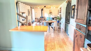 A spacious kitchen with wooden flooring, a dining area with a round table, and a staircase leading to another level. - Charming Breton Penty 40m from the ocean (Penmarc'h)