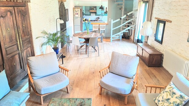 A cozy living room with wooden flooring, two armchairs, a sofa, and a dining table. A staircase leads to an upper level. - Charming Breton Penty 40m from the ocean (Penmarc'h)