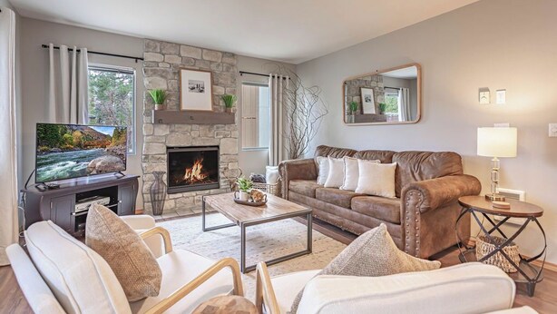 A living room with a stone fireplace, a television, a sofa, and a coffee table. - ✓ King Bed+  ✓ Sleeps 8 ✓ Walk to Downtown + Coaster ✓ Ground Floor (Leavenworth)