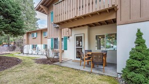 A two-story house with a balcony, a patio with a table and chairs, and a small garden area. - ✓ King Bed+  ✓ Sleeps 8 ✓ Walk to Downtown + Coaster ✓ Ground Floor (Leavenworth)