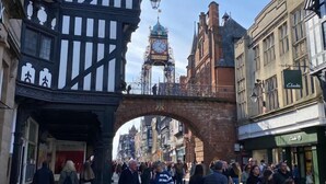 A pedestrian street with historic buildings, a prominent clock tower, and an archway. - Grosvenor Place Guest House (Chester)