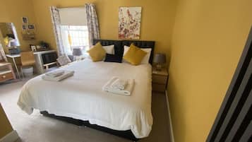 Habitación de hotel con una cama grande, un escritorio, una silla y una ventana con cortinas.