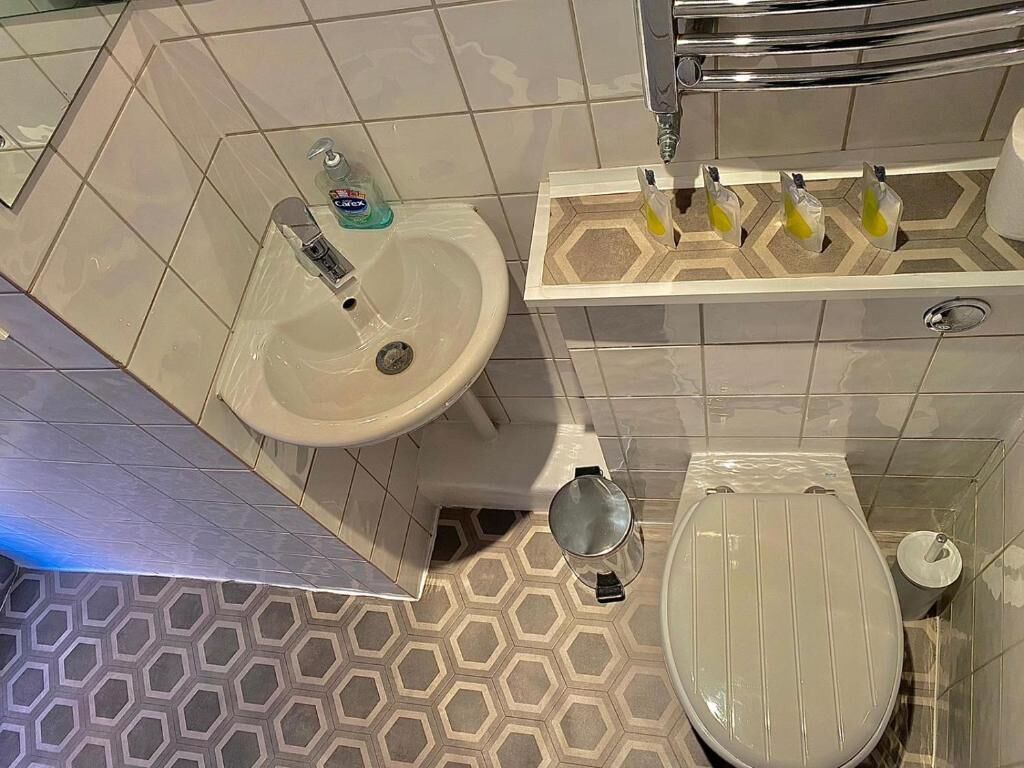 A bathroom with a hexagonal patterned floor, a white sink, and a toilet with a lid.