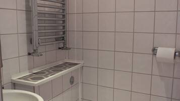 Um banheiro pequeno revestido com azulejos, com vaso sanitário, pia e porta-toalhas.