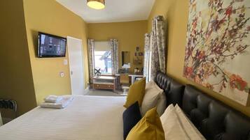 A hotel room with a bed, a television, a desk, and a chair.