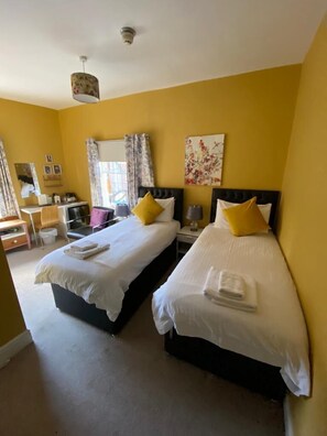 Une chambre d’hôtel avec deux lits, un bureau et une chaise.