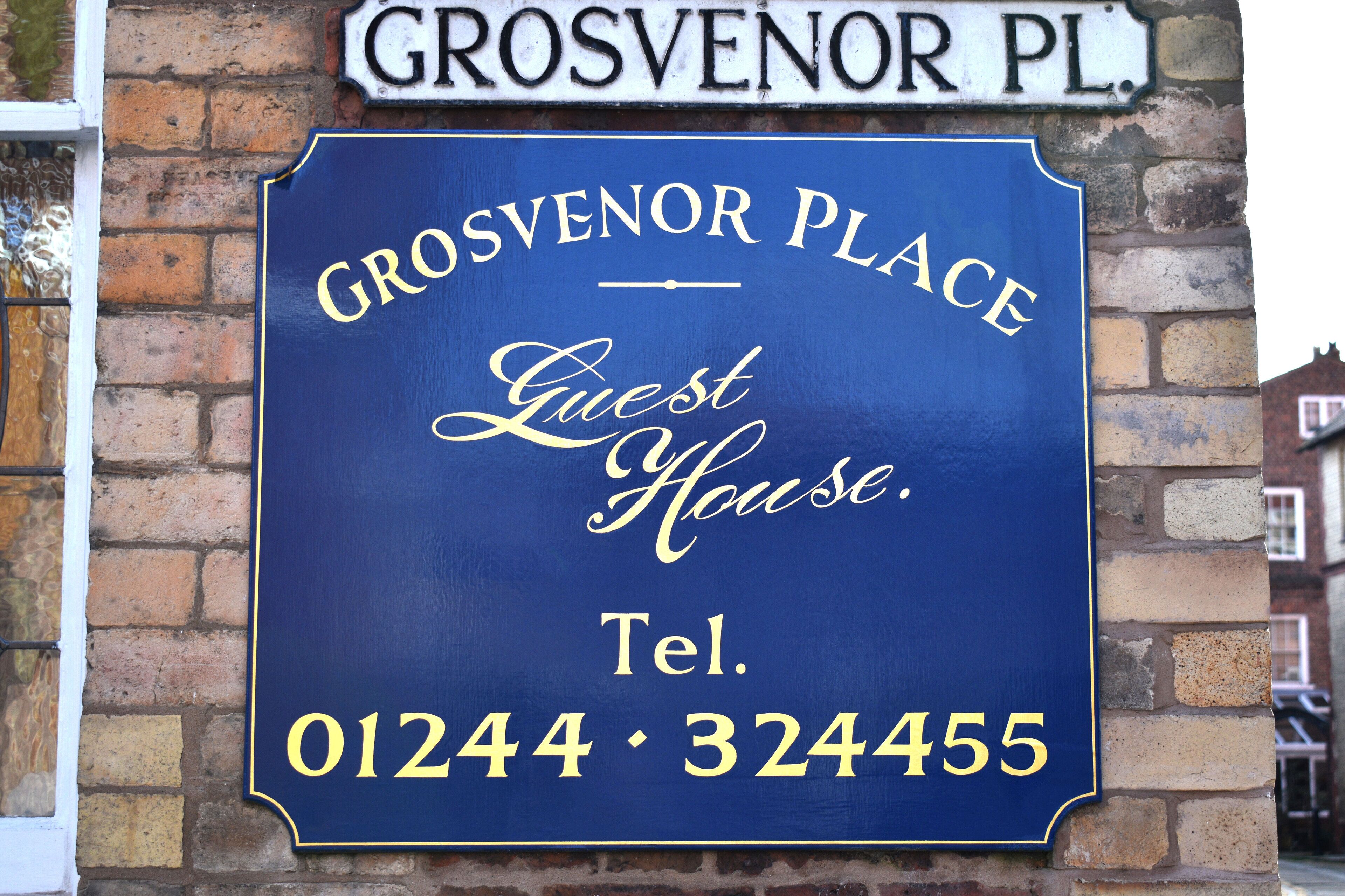 Ein blaues Schild mit weißer Schrift, das das Gästehaus Grosvenor Place kennzeichnet.
