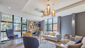 A modern living room with a sofa, chairs, a coffee table, and a bookshelf. - Cosy studio à 5 min du centre-ville | Piscine (Aix en Provence)