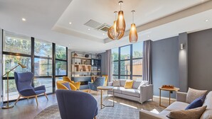 Una sala moderna con un sofá, sillas, una mesa de centro y una estantería.