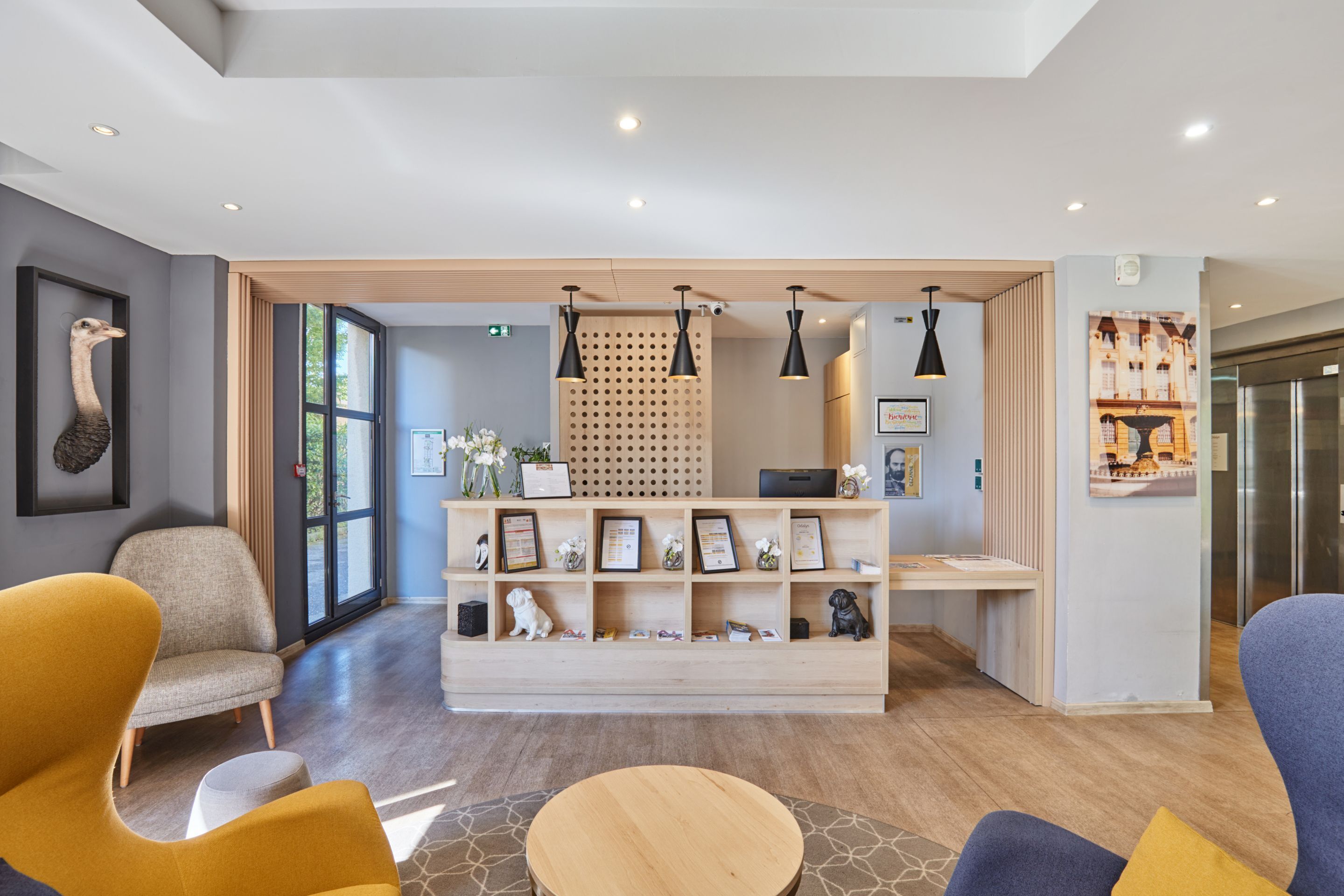 Een receptiegedeelte met een houten receptiebalie, ingelijste certificaten en een zithoek met stoelen.