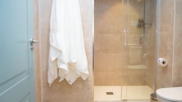 Een badkamer met een douchecabine van glas, een toilet en een handdoek aan de muur.