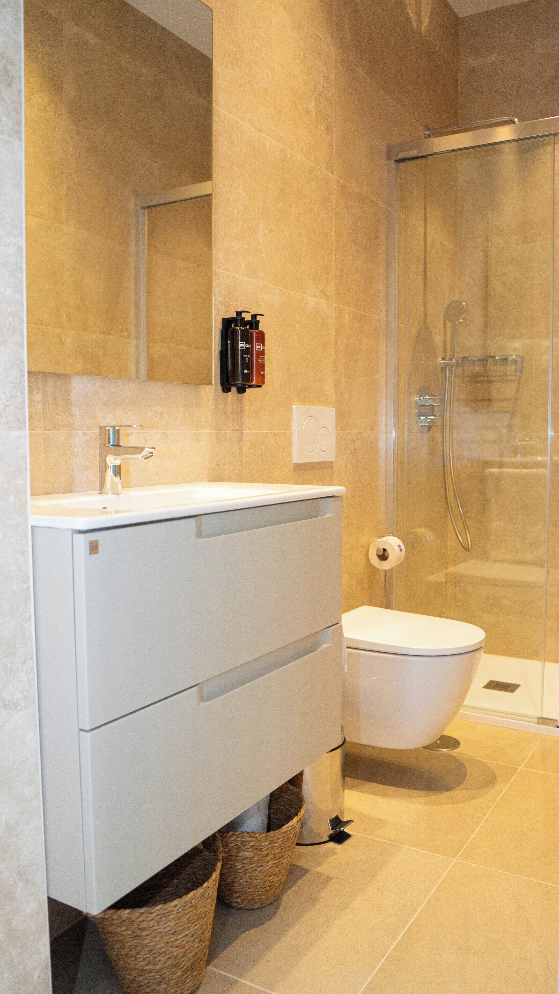 A modern bathroom with a white vanity, a glass shower enclosure, and a toilet.