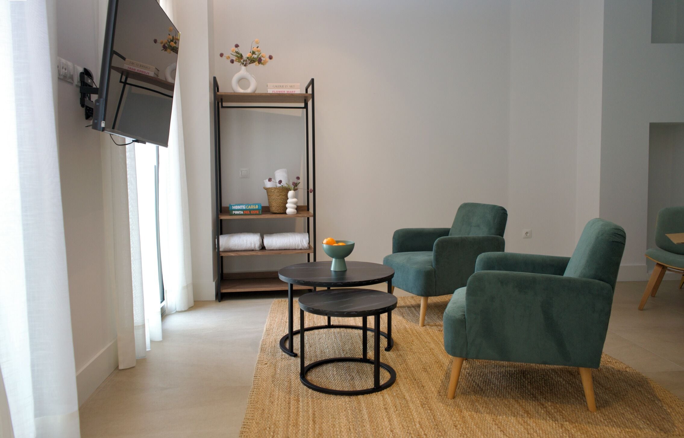 A modern living room with a sofa, two armchairs, a coffee table, and a TV mounted on the wall.