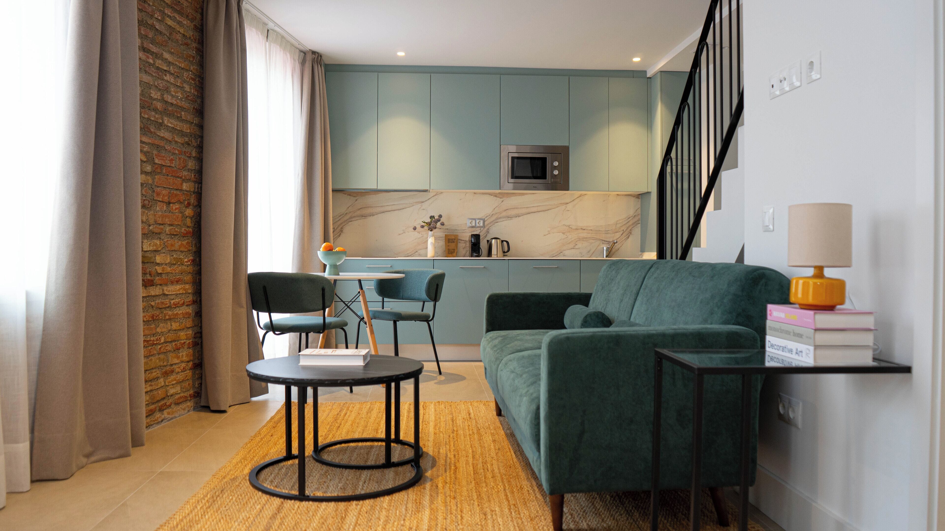 A modern living room with a sofa, a coffee table, and a dining area with chairs and a small table.