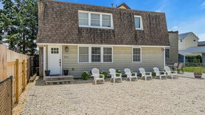 A two-story house with a front porch, a gravel driveway, and several white chairs arranged outside. - Fast WiFi | Linen+Towels | Espresso | Pet Friendly (Seaside Heights)