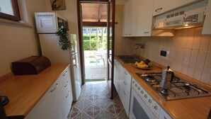Una cocina compacta con gabinetes blancos, una estufa a gas y un refrigerador.