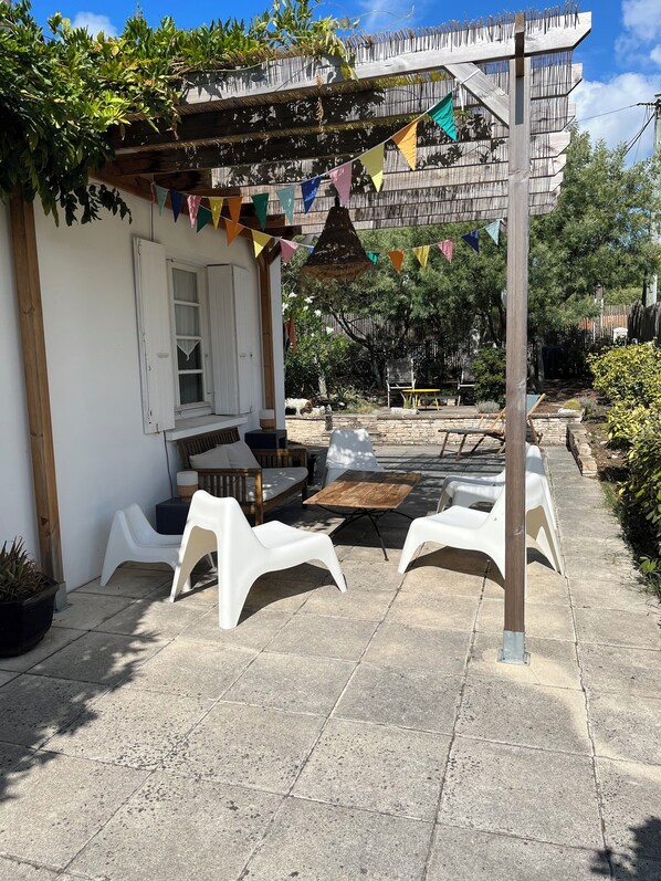 Een terras met buitenmeubilair, een pergola en kleurrijke vlaggen.