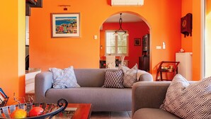 Una sala de estar con un sofá gris, cojines estampados y un frutero sobre una mesa de centro.