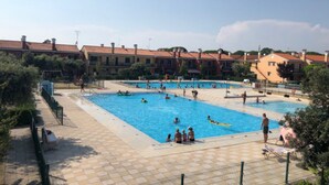 Un espace piscine comprenant plusieurs bassins, entouré de bâtiments aux toits recouverts de tuiles rouges.