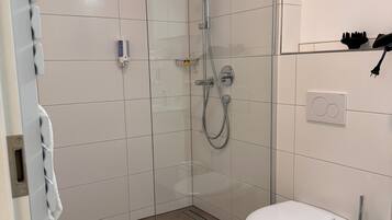 Een moderne badkamer met een douchecabine van glas, een wit toilet en een handdoekhouder.