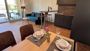 A modern apartment with a dining area, kitchen, and a sofa. - SONNENHOF Apartments (Bad Duerrheim)