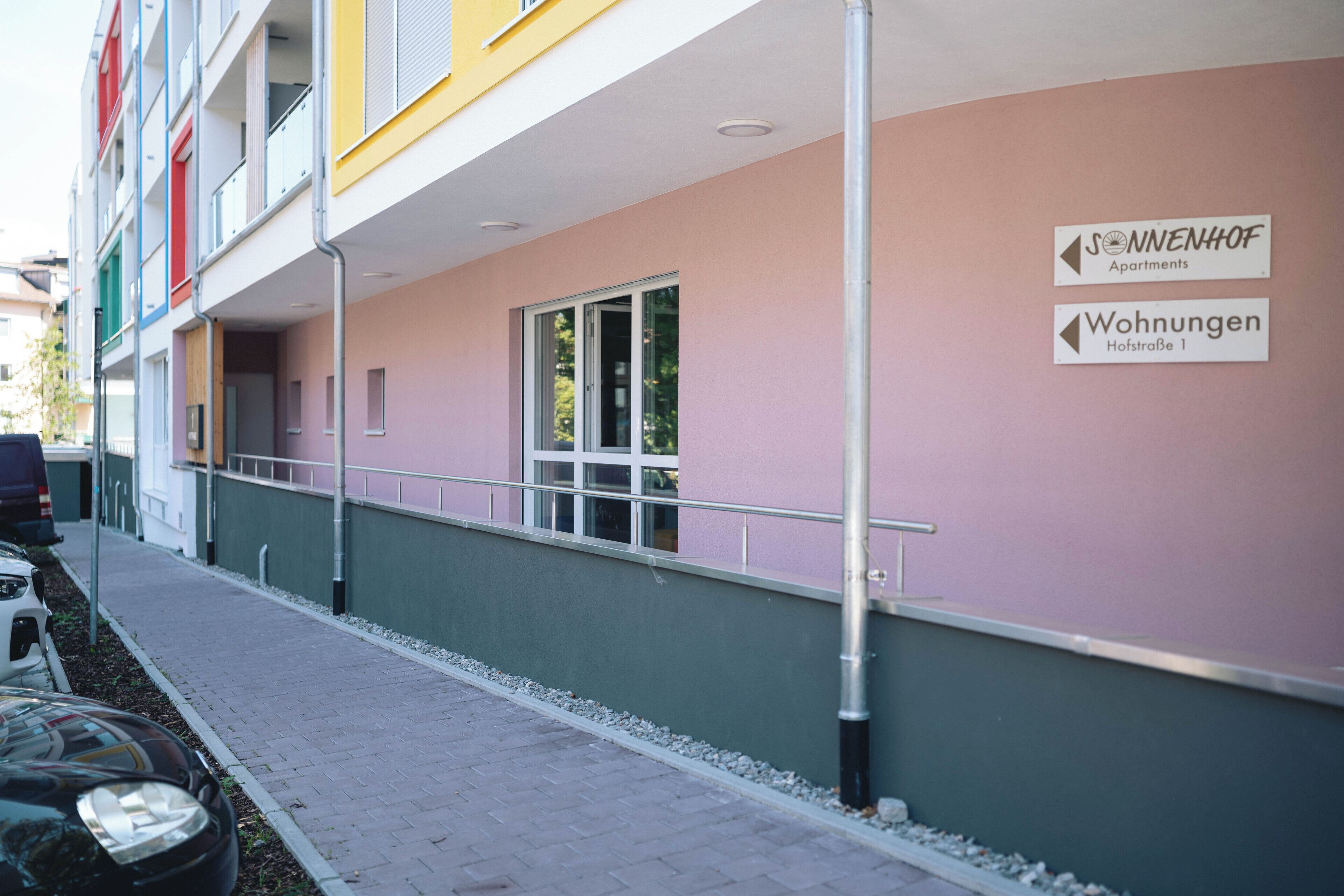 A multi-story building with balconies, a sign indicating 'Sonnenhof Apartments' and 'Wohnungen Hofstraße 1'.