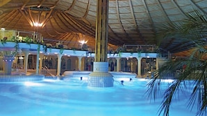 A large indoor swimming pool with a central column and a wooden ceiling structure. - SONNENHOF Apartments (Bad Duerrheim)
