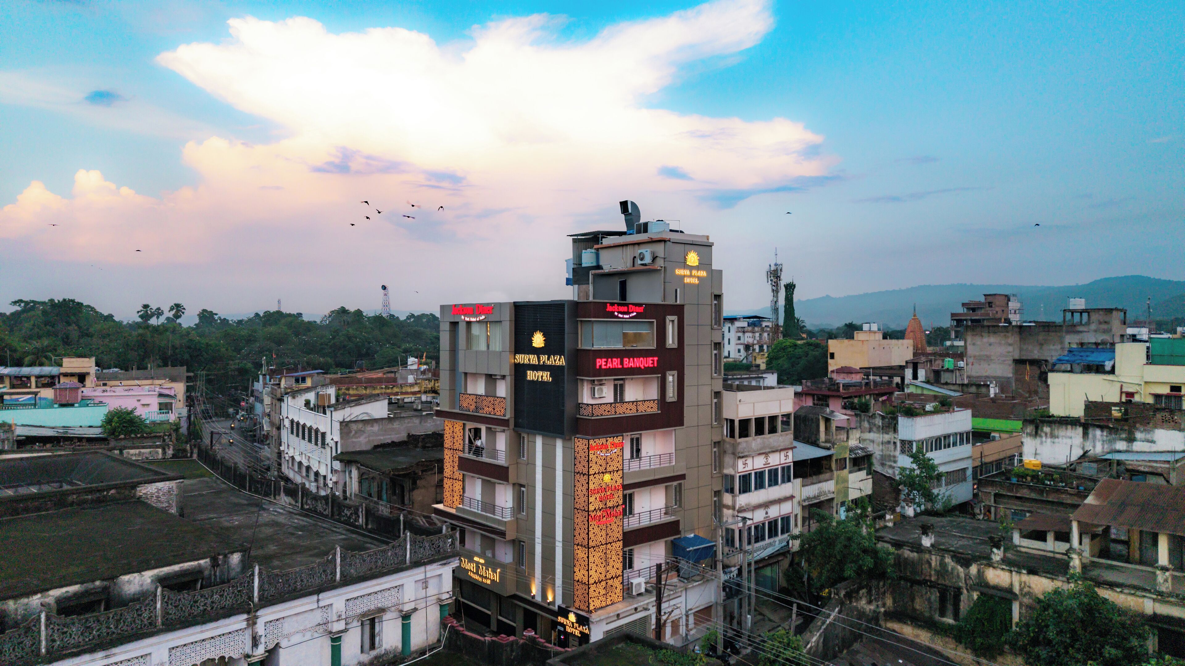 Un hotel con varios pisos, un letrero llamativo y vistas de la ciudad circundante.