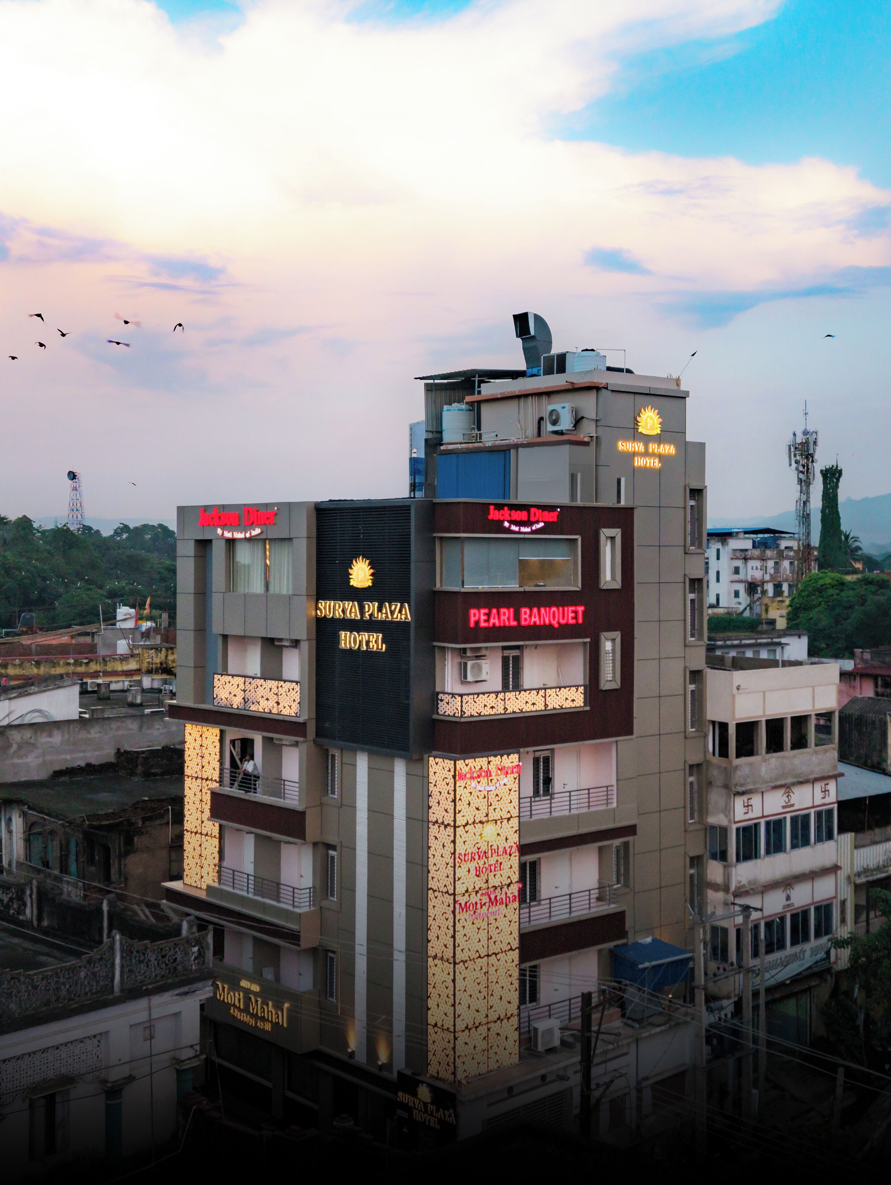 Ett hotell med flera skyltar, bland annat "Surya Plaza Hotel", "Pearl Banquet" och "Moti Mahal".