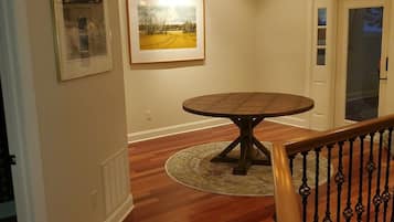 A dining area with a round table, a chandelier, and framed pictures on the wall.