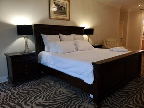 A standard hotel room with a bed, two bedside tables, a lamp, and a zebra-patterned carpet. - The Best of the Greenbrier (White Sulphur Springs)