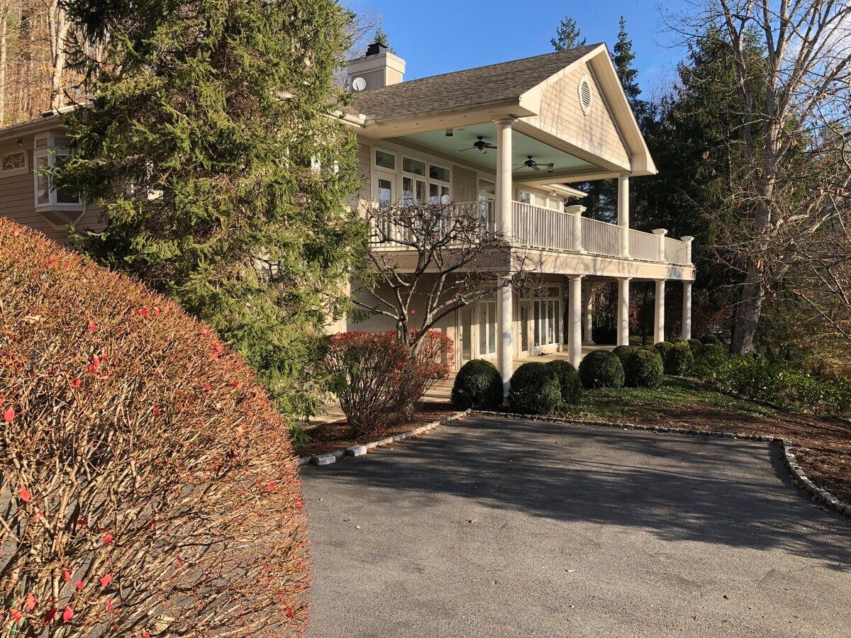 A two-story house with a covered porch and a driveway.