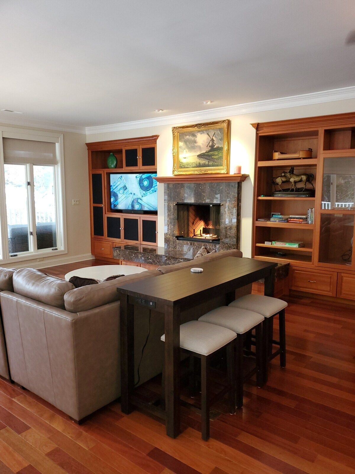 A living room with a fireplace, a sofa, a dining table with chairs, and a bookshelf.