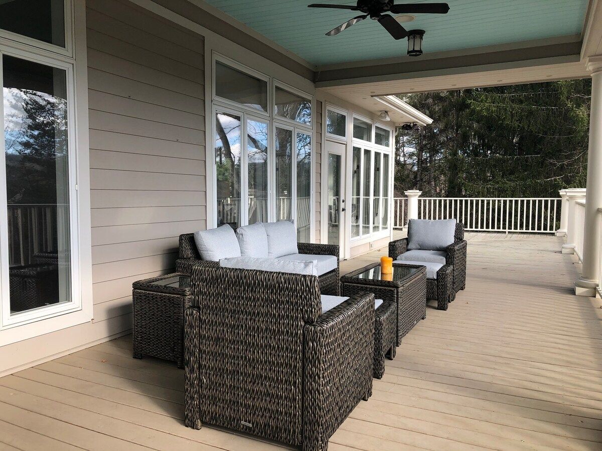 A covered outdoor seating area with wicker furniture and a ceiling fan.